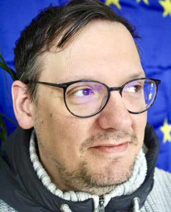 Eine Portraitaufnahme von Erich Adam vor einer Europafahne